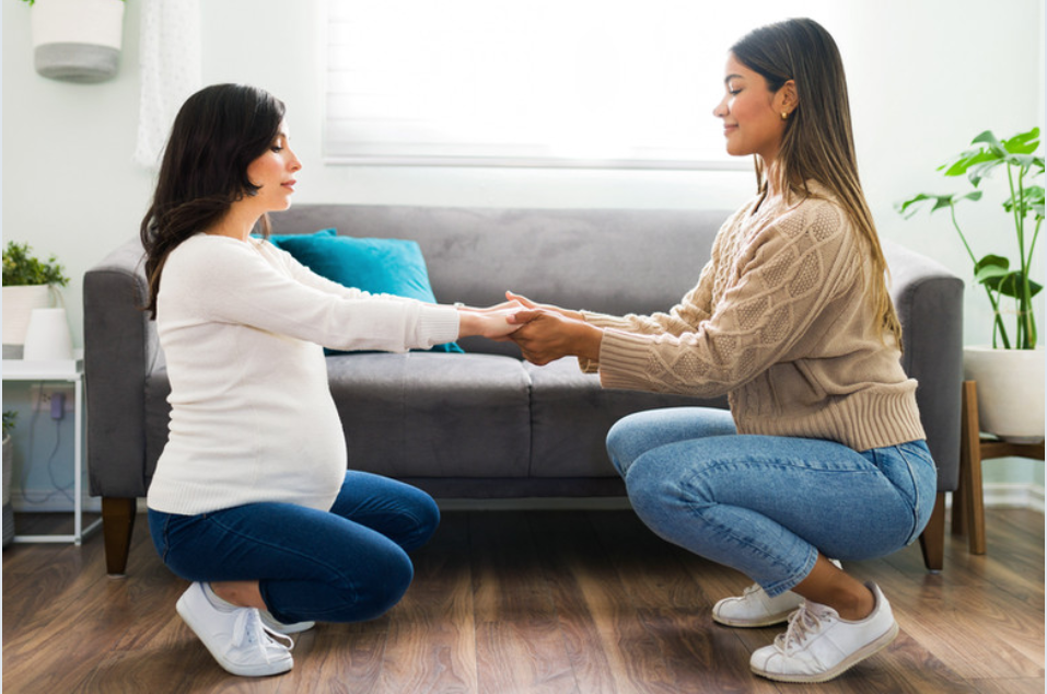 pregnant mom preparing her pelvis for birth by doing deep squats with her prenatal trainer