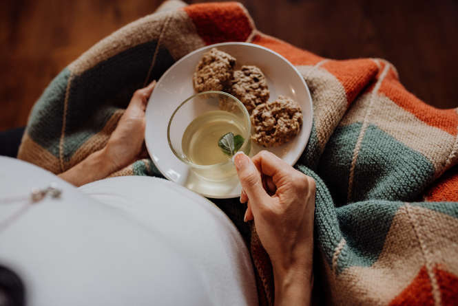 postpartum mom sits and relaxes with tea and lactation snacks