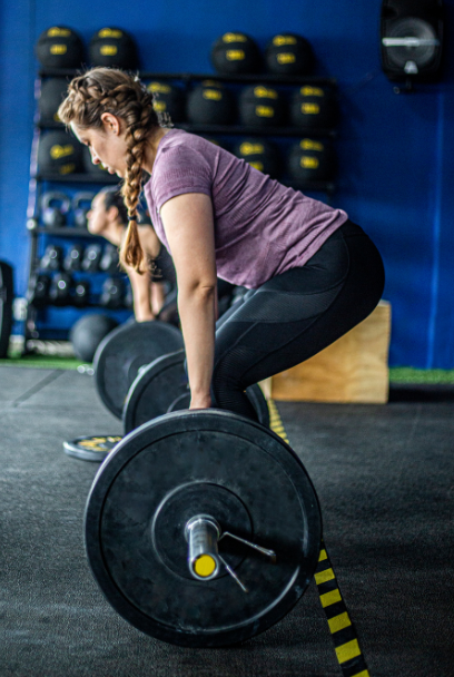 pregnant mom lifts a barbell during one of her prenatal workouts to improve her strength